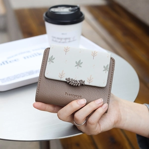 Detailed view of leaf pattern print and leather flap on a small folding wallet