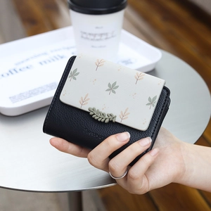 Detailed view of floral printed PU leather wallet with green leaf clasp and logo