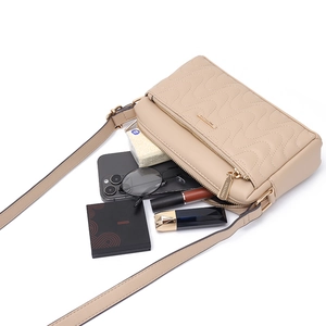 Sac bandoulière matelassé beige avec sangle réglable montrant l'espace de rangement