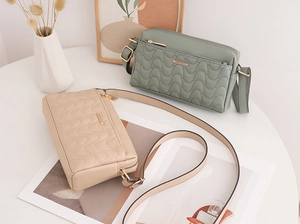 Détail de sacs bandoulière matelassés ondulés élégants en vert et beige avec dorures