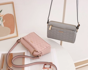 Détail de sacs bandoulière matelassés rose et gris avec accessoires dorés