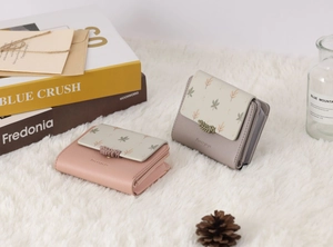Detail of sweet printed short PU leather wallets with leaf buckles on a plush background