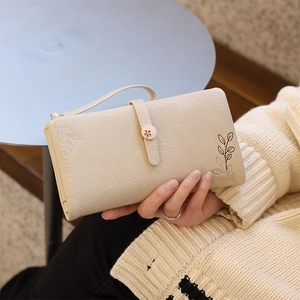 Detail of cream long wallet featuring leaf embroidery and a golden flower clasp