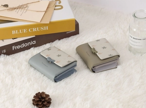 Close-up of small floral print and leaf-shaped silicone buckle on textured PU leather wallets