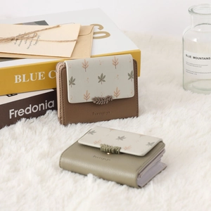 Close-up of vintage brown and green PU leather trifold wallets with leaf print on plush