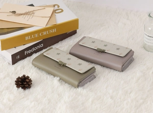 Détail de portefeuilles en cuir PU à fleurs avec boucle feuille sur fond en peluche blanc
