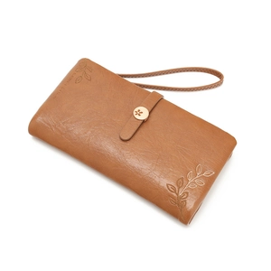 Detail view of dark brown leather long wallet with leaf embroidery and golden metal clasp
