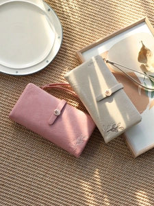 Detail of long wallets with floral embroidery, leaf motifs and detachable wrist straps