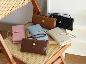Detail shot of six colorful long wallets with leaf embossing on a wooden chair