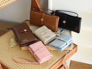 Detail view of multi-color long leather wallets with leaf embroidery and gold flower clasps