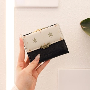 Close-up of floral print tri-fold wallet with leaf buckle and metal gold clasp detail