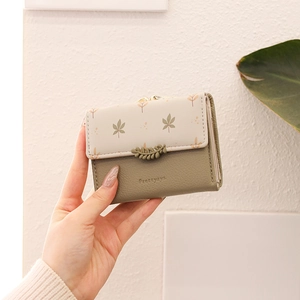 Close-up of trifold wallet with leaf buckle and elegant print on faux leather