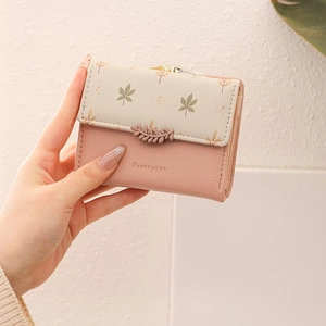 Women's short tri-fold pink wallet with leaf buckle and printed pattern in hand
