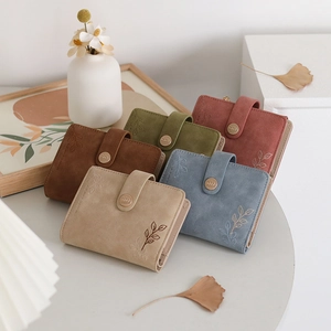 Close-up of multi-colored PU leather wallets with leaf embossing and metal buckle details