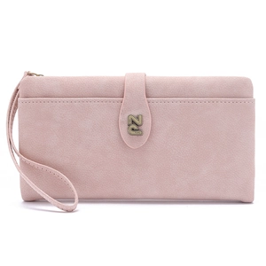 Close-up of pale pink leather wallet featuring bronze metal logo and wristlet strap detail