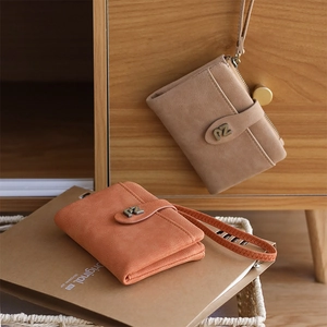 Close-up of mini wristlet wallets in tan and orange suede with metal PZ logo