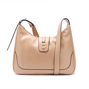 Détail d'un sac bandoulière beige avec boucle en D dorée et logo de la marque