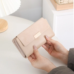 Détail d'un long portefeuille beige avec rabat mat et fermoir en métal doré de marque