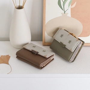 Detailed view of trifold PU leather wallets with floral print and leaf-shaped metal clasps