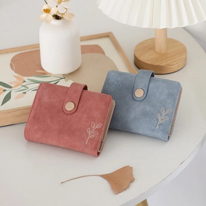 Close-up of matte PU leather wallets in dusty rose and blue with leaf embossing