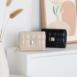 Detailed view of quilted PU leather wallets in beige and black with gold zip closure