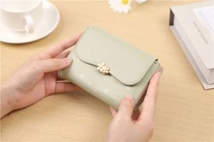 Detail of mint green floral wallet featuring a delicate gold double petal metal clasp