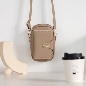 Detail of taupe pebbled leather phone bag with dual compartments and gold oval metal buckle