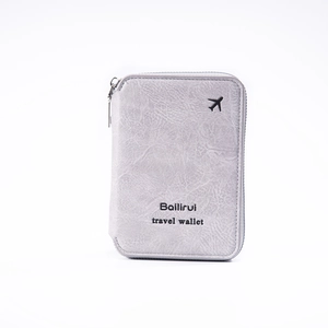 Close-up of light gray leather passport wallet with metal zipper and airplane icon