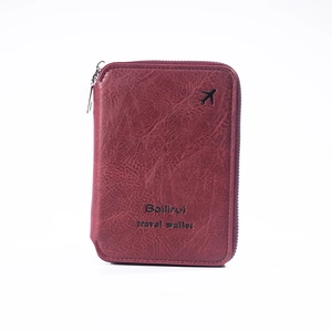 Detail of burgundy leather travel wallet with airplane icon and smooth zipper closure