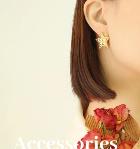 Detail of gold star earrings with 18k plating and beaded texture on model ear