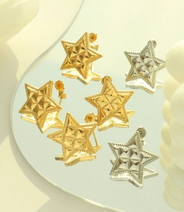 Detail of star-shaped earrings in gold and silver with diamond-textured finish on mirrors