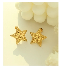 Detail view of gold star stud earrings with quilted texture and beaded edge design