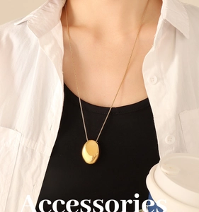 Collier élégant doré avec pendentif ovale porté par un mannequin pour un style chic