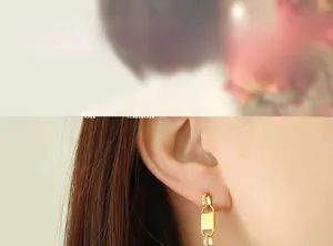 Detail of gold chain drop earrings with textured metal rings and pearl accent