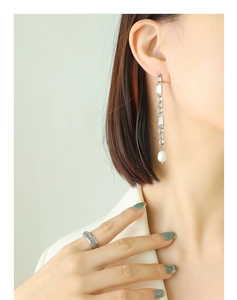 Detail of silver long chain earrings with freshwater pearl and textured metal ring