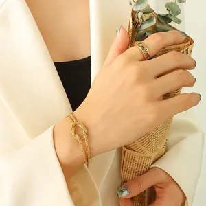 Elegant gold-plated knot bracelet and textured chain ring on model with aesthetic background