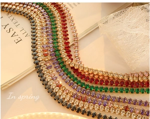 Detail of colorful oval zirconia tennis necklaces on white lace with golden plating