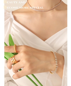 Elegant gold necklace and bracelet set with round zircon stones worn by a model