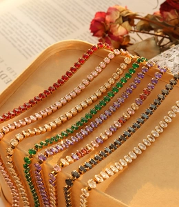 Detailed close-up of multi-colored zircon gemstone necklaces on an elegant beige tray