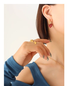 Nahaufnahme goldener Herzohrringe mit roter Emaille an einem Model für einen eleganten Look