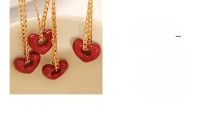Makroaufnahme einer Herzkette in Rot mit Goldkette an einer Keramiktasse hängend