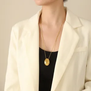 Collier minimaliste doré avec pendentif ovale et bague chaîne articulée sur un mannequin
