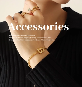 Close-up of golden Cuban chain bracelet with letter B pendant and minimalist rings