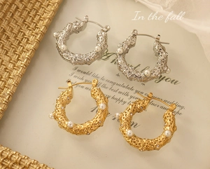 Macro detail of French vintage hammered U-shaped earrings with pearls and zircons