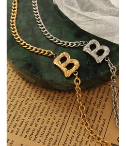 Macro detail of gold and silver B letter pendants with bamboo texture on Cuban chains