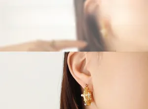 Macro detail of hammered gold U-shape earrings featuring white pearls and zircon insets