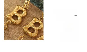 Macro shot of gold-plated Cuban link bracelet featuring a B-shaped logo and bamboo texture