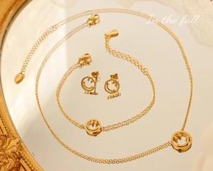 Detailansicht des 18K vergoldeten Schmucksets mit hohlen Smileys auf einem Spiegel