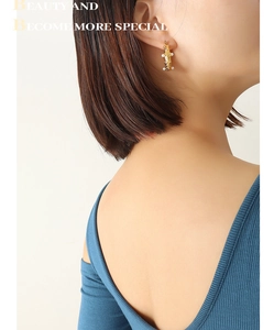 Detail of gold hammer-textured U-shape earrings with pearls worn by a model