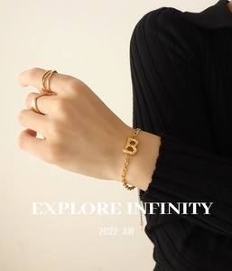 Close-up of gold Cuban chain bracelet with letter B pendant and textured rings set